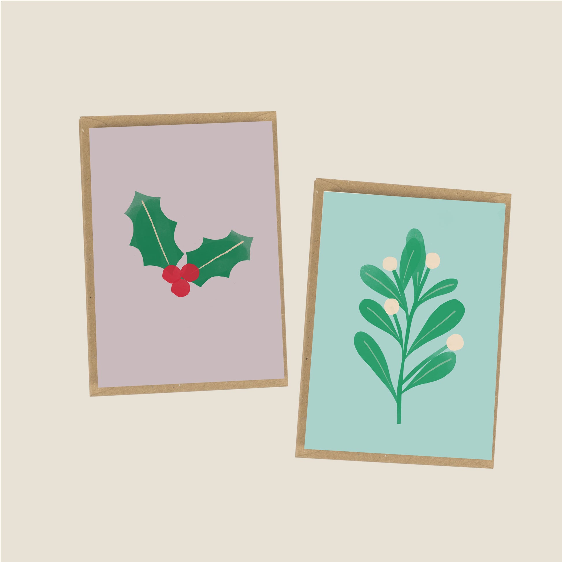 image of two christmas cards one with holly and one with mistletoe on a plain background