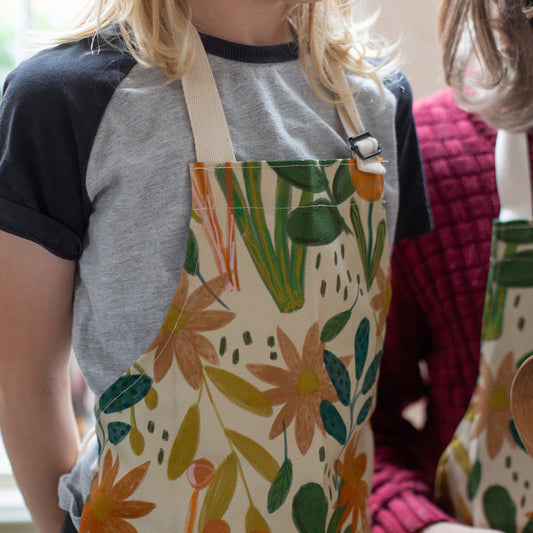 Kid's floral bud design apron with adjustable strap. 
