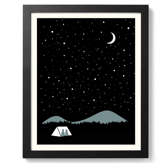 Framed artwork of a night sky with stars, mountains, and a tent under a black frame.