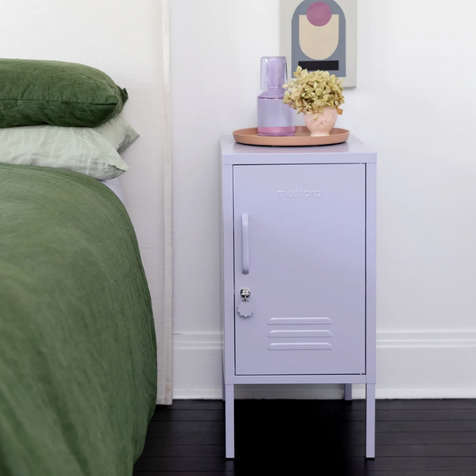 Bedroom with a green bed and a purple mustard made locker with decorative items.