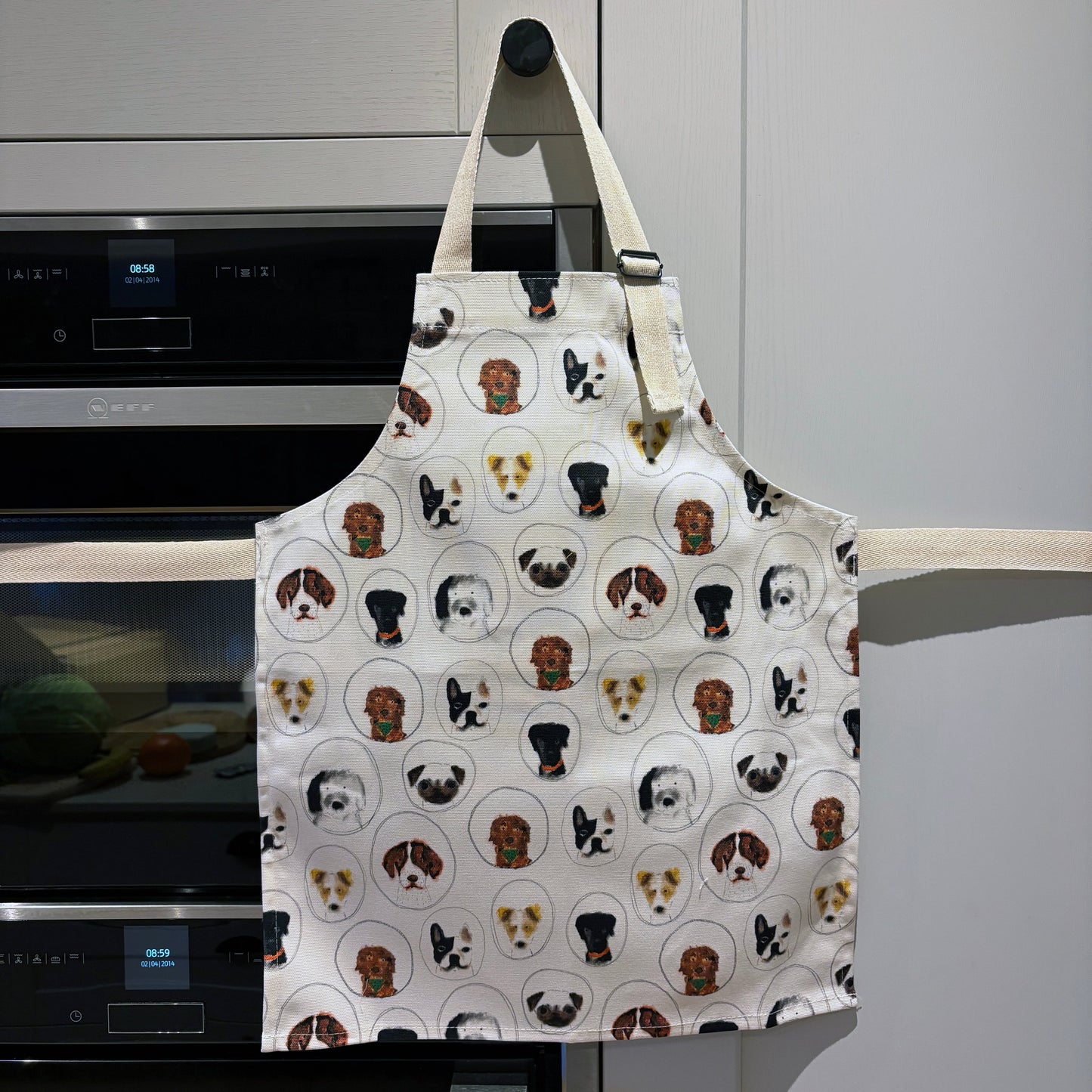 Apron with dog pattern hanging on a kitchen cupboard