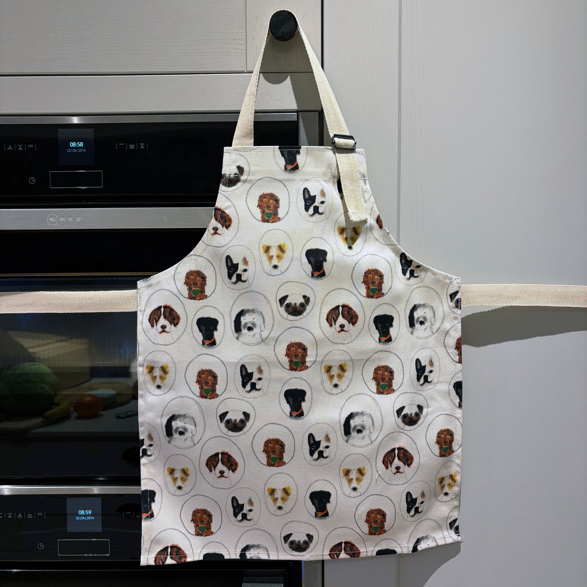 Apron with dog pattern hanging on a kitchen cupboard