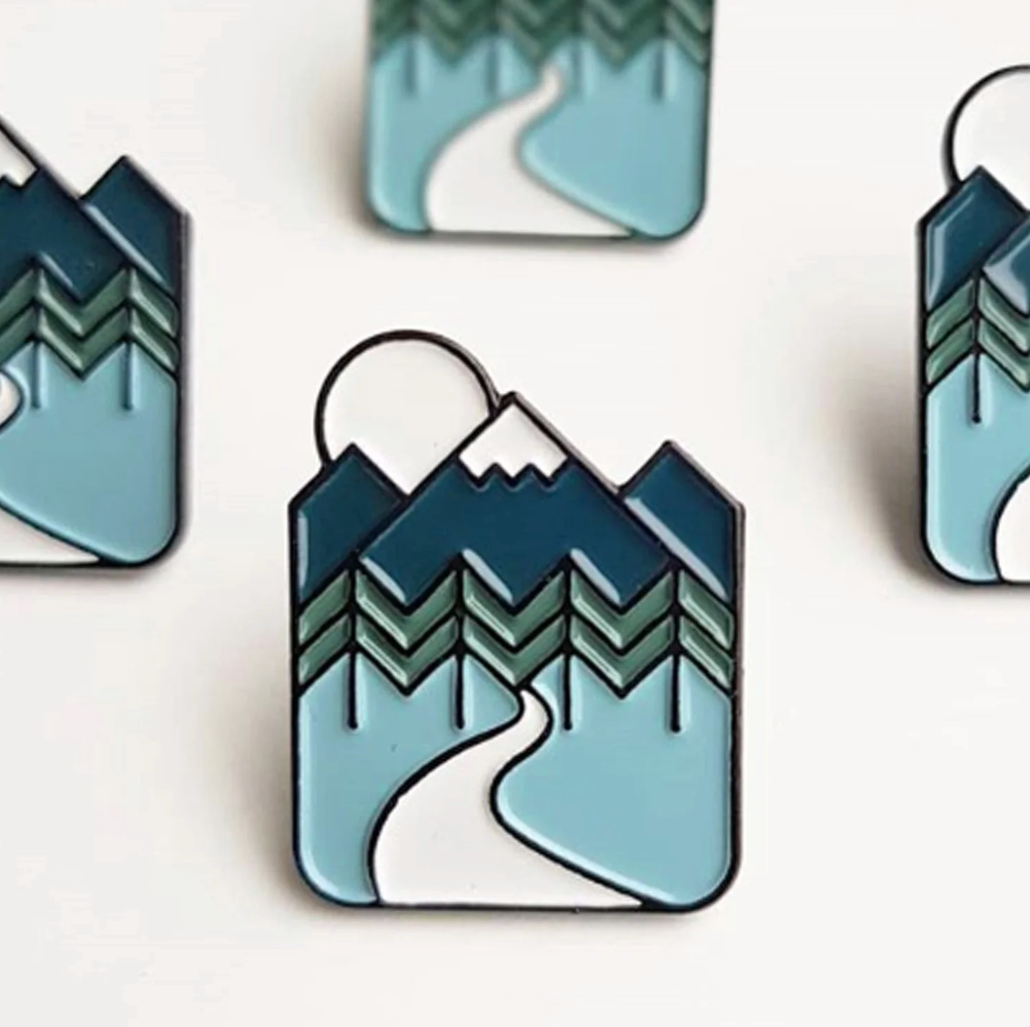 Mountain and trail pin badge on a blue background