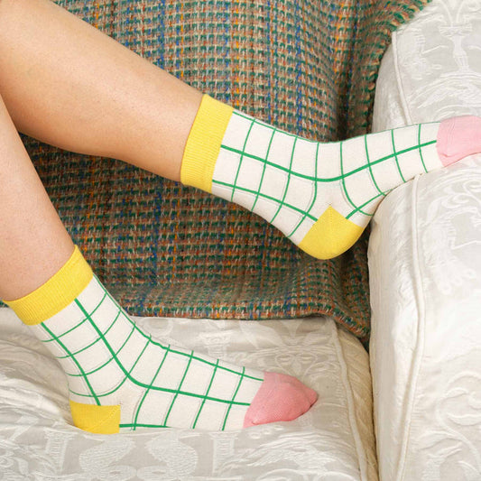 Person wearing socks with grid pattern and pink hearts on a textured surface