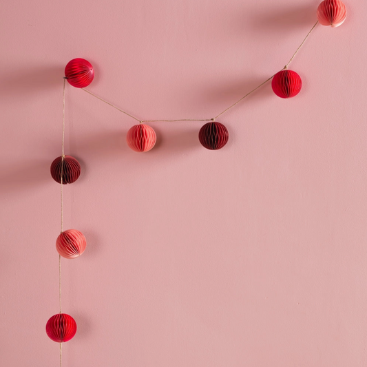 pink and red paper origami garland hung against a pink wall