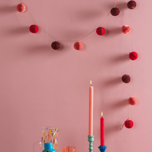 pink and red origami garland hung against a pink wall