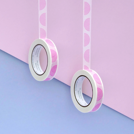 Two rolls of washi tape with a pink and white geometric pattern, hanging against a split pastel pink and blue background.
