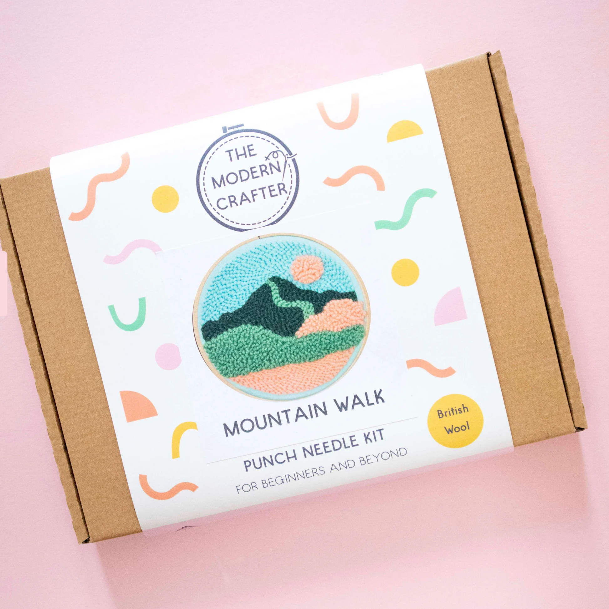 Punch needle kit packaging with mountain design on a pink background