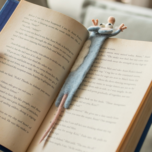 Open book with a plush mouse bookmark on a blurred indoor background