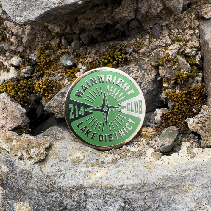 Green and gold badge with 'Wainwright Club' text on a stone background
