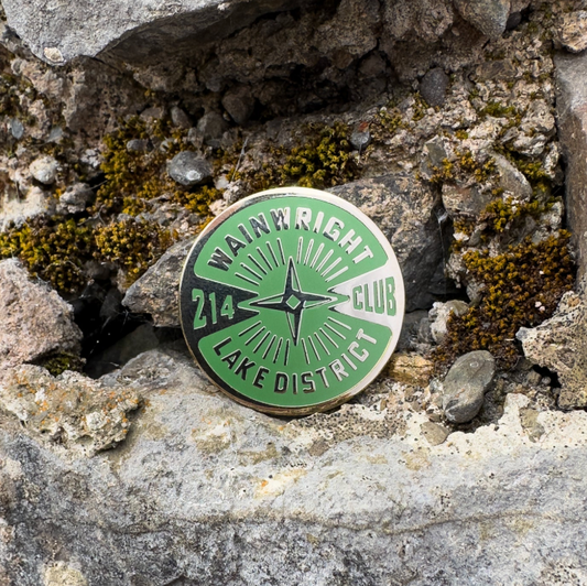 Green and gold badge with 'Wainwright Club' text on a stone background