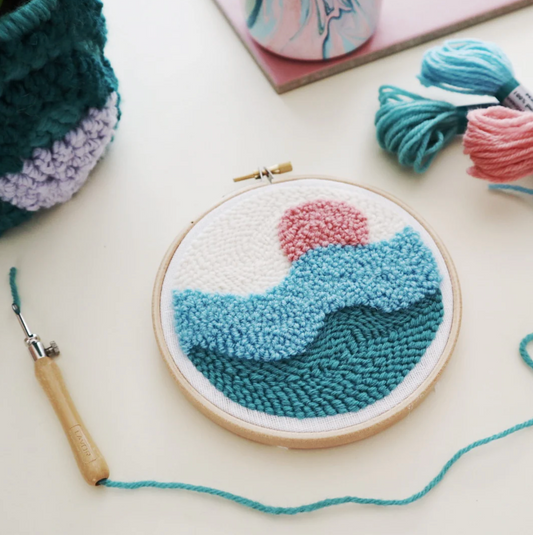 Handmade yarn art with a wave design in an embroidery hoop on a light surface.