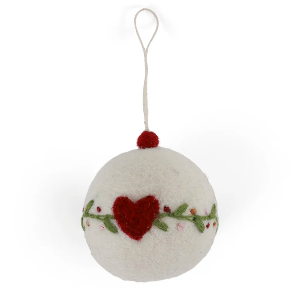 A white felt Christmas ornament shaped like a sphere with a hanging loop, decorated with a red heart, green vine, and small pink and red berries, shown on a white background.