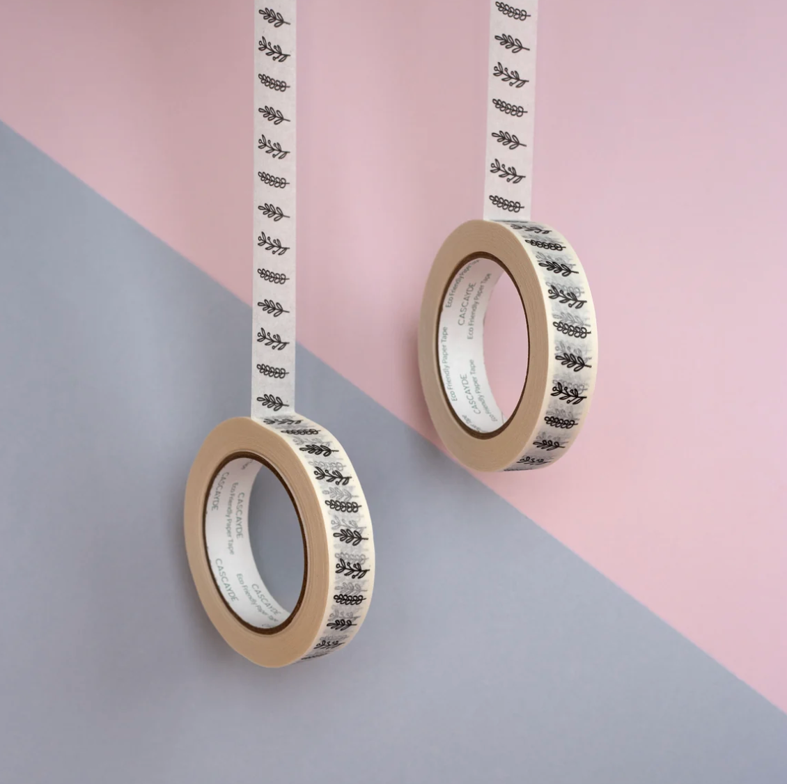 Two rolls of tape with black text on a pink and gray background