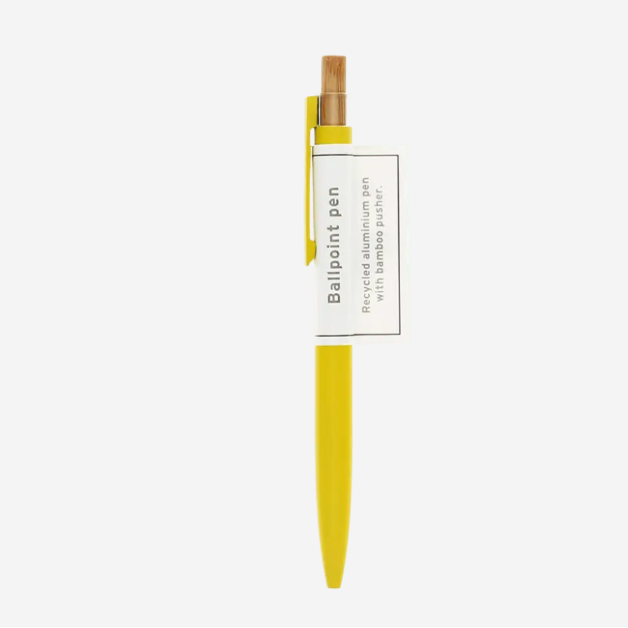 A yellow ballpoint pen with a bamboo clip and a white paper label wrapped around the middle, shown against a light gray background.